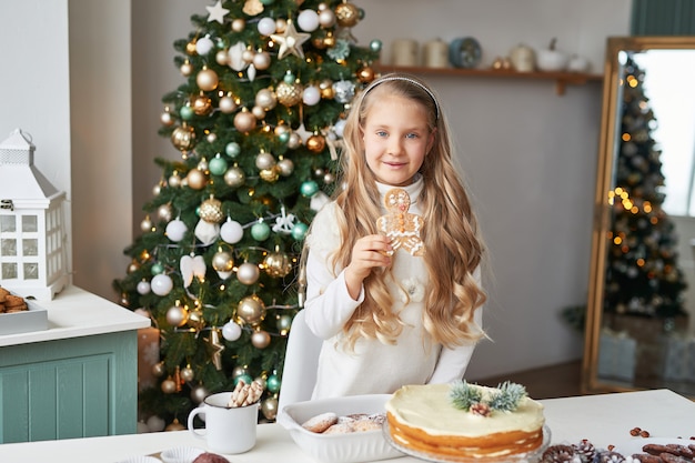 ragazza bionda nella cucina del nuovo anno con cupcakes e dolci