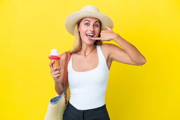 Ragazza bionda uruguaiana in estate che tiene il gelato isolato su sfondo giallo facendo il gesto del telefono Chiamami indietro segno