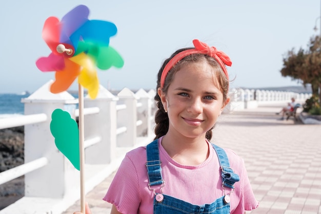 Ragazza blueyed che tiene un mulino a vento colorato in movimento Concept lifestyle spiaggia giornata passeggiata sul mare