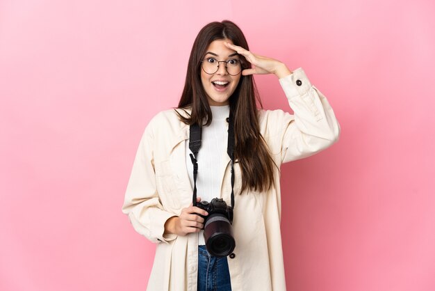 Ragazza brasiliana del giovane fotografo isolata sul colore rosa con l'espressione di sorpresa