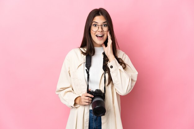 Ragazza brasiliana del giovane fotografo isolata sulla parete rosa con espressione facciale sorpresa e scioccata