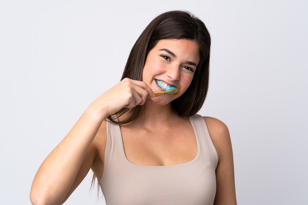 Ragazza brasiliana dell'adolescente che pulisce i suoi denti sopra fondo bianco isolato