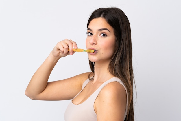 Ragazza brasiliana dell'adolescente che pulisce i suoi denti sopra fondo bianco isolato