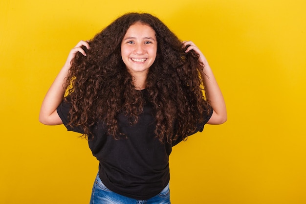 Ragazza brasiliana latinoamericana per capelli afro sfondo giallo mani sulla testa capelli simbolo ricci capelli ricci capelli pettinati bei capelli prodotti per capelli