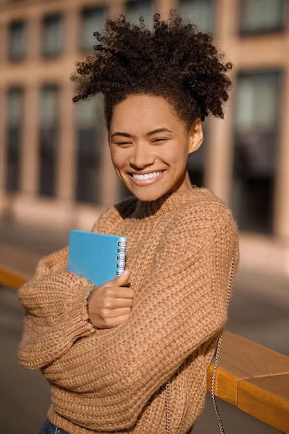 Ragazza brillante che abbraccia quaderno all'aperto