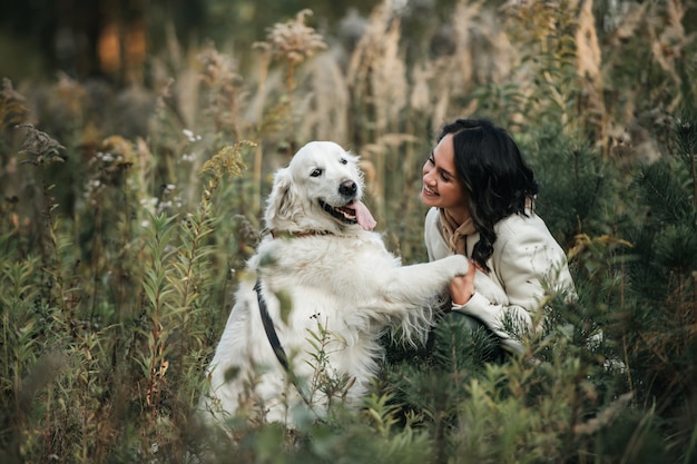 Ragazza bruna con cane golden retriever bianco nel campo