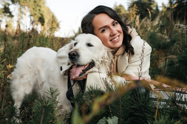 Ragazza bruna con cane golden retriever bianco nel campo