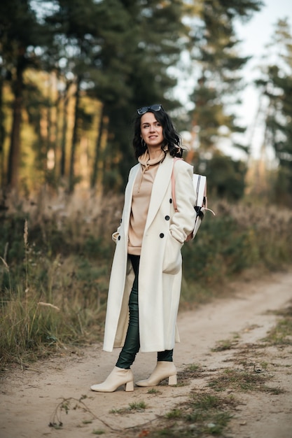 ragazza bruna con zaino sul sentiero nel bosco