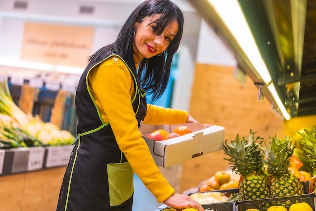 Ragazza bruna della frutta che lavora per ordinare i frutti in uno stabilimento di fruttivendolo