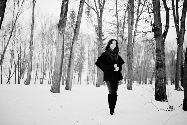 Ragazza bruna in maglione verde, cappotto e sciarpa rossa all'aperto il giorno d'inverno serale.