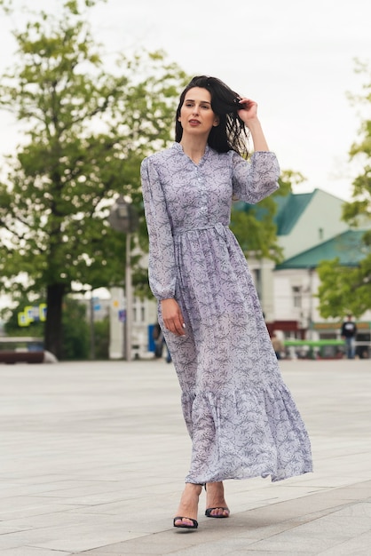 ragazza bruna in posa in una strada di città Donna d'affari piuttosto bella in abito elegante sullo sfondo della città