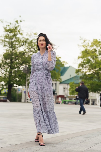 ragazza bruna in posa in una strada di città Donna d'affari piuttosto bella in abito elegante sullo sfondo della città