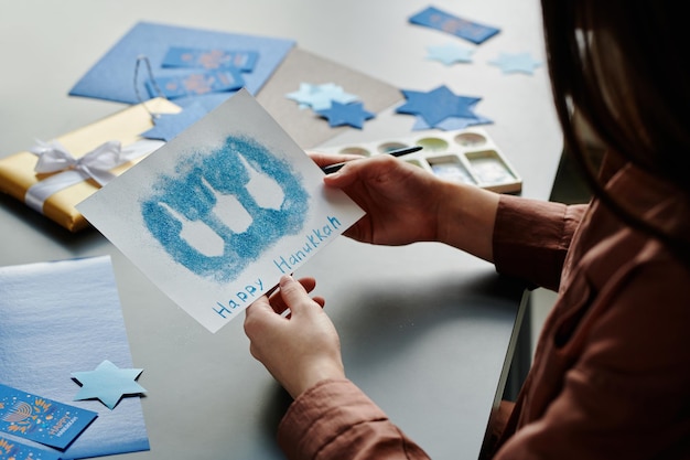 Ragazza bruna irriconoscibile con una cartolina di Hanukkah fatta a mano