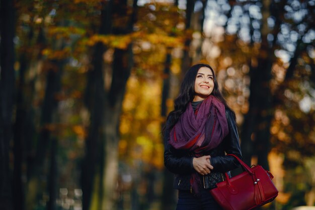 ragazza bruna rilassante al parco durante l&#39;autunno