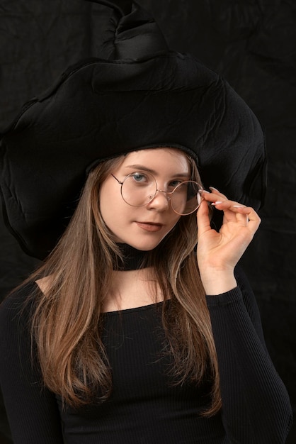 Ragazza carina a forma di strega con cappello a punta e occhiali Ritratto di adolescente in costume di Halloween primo piano Studenti di Hogwarts