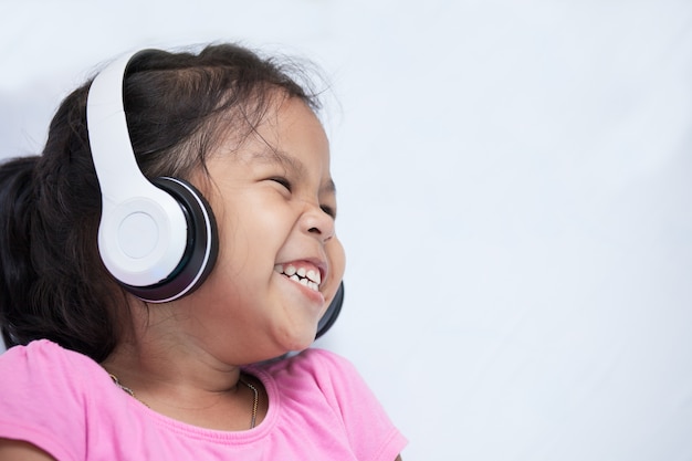 Ragazza carina asiatica bambino in cuffie ascoltando musica