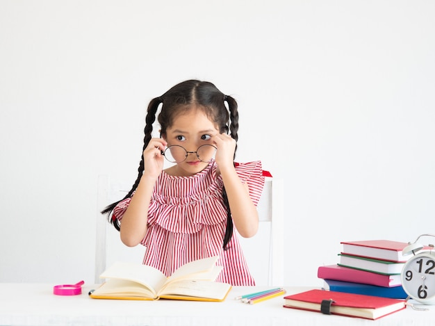 Ragazza carina asiatica con il libro sulla scrivania