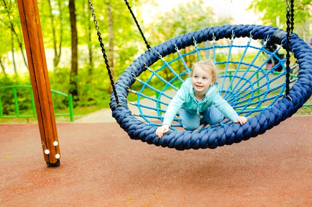 Ragazza carina bambino caucasico 4 anni divertirsi su uno scivolo in un parco giochi