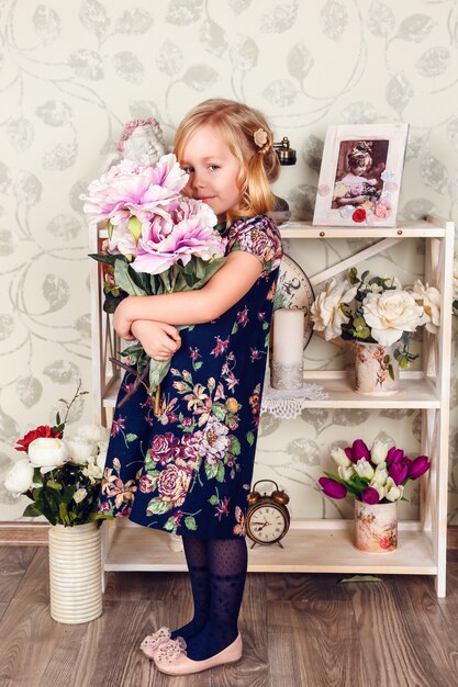 Ragazza carina bambino piccolo con fiori di primavera, bambina felice con cesto di fiori.