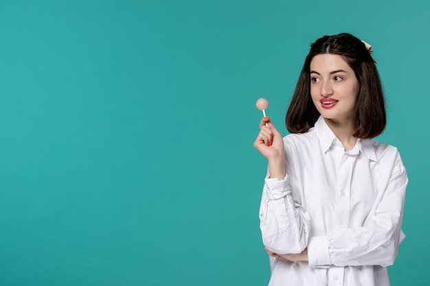 Ragazza carina bella bruna ragazza dolce in camicia bianca che guarda a sinistra con caramelle bianche