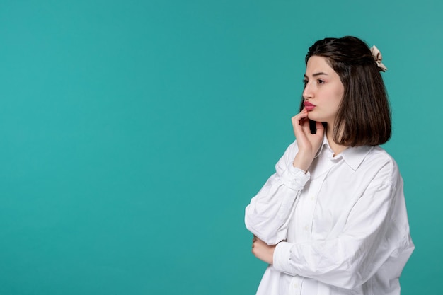 Ragazza carina bella giovane ragazza castana graziosa in camicia bianca che pensa e molto concentrata