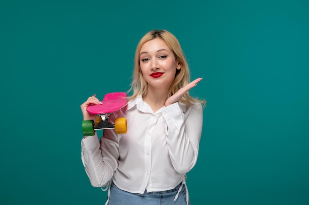 Ragazza carina bionda bella ragazza in una camicia bianca ordinata agitando le mani che tengono skateboard rosa