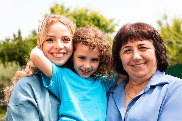 Ragazza carina che abbraccia madre e nonna all'aperto