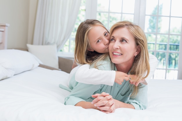 Ragazza carina che bacia la sua madre sorridente