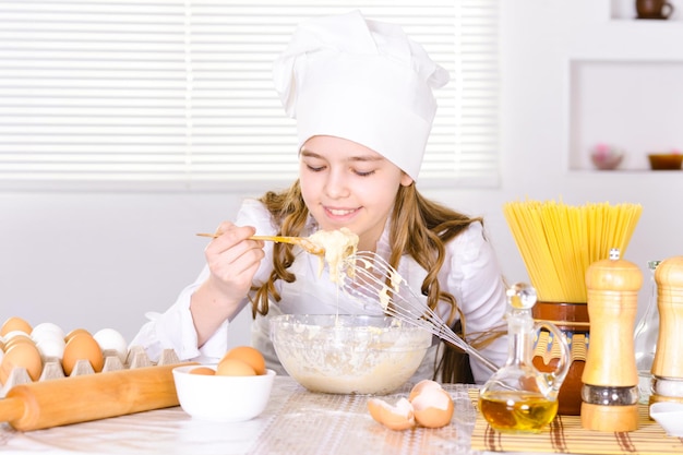 Ragazza carina che cucina in cucina a casa