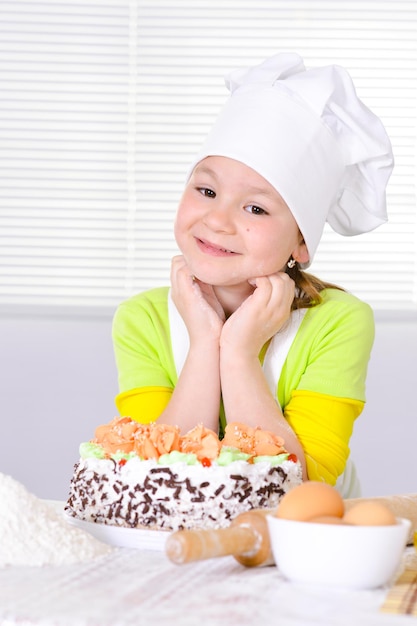 Ragazza carina che cuoce la torta in cucina a casa