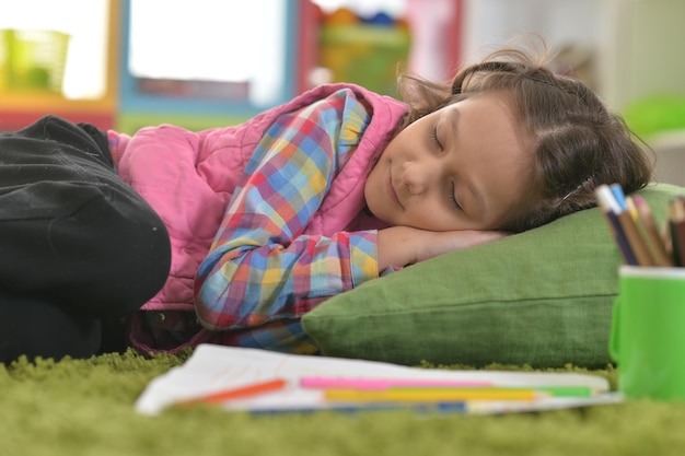 Ragazza carina che dorme sul cuscino sul pavimento