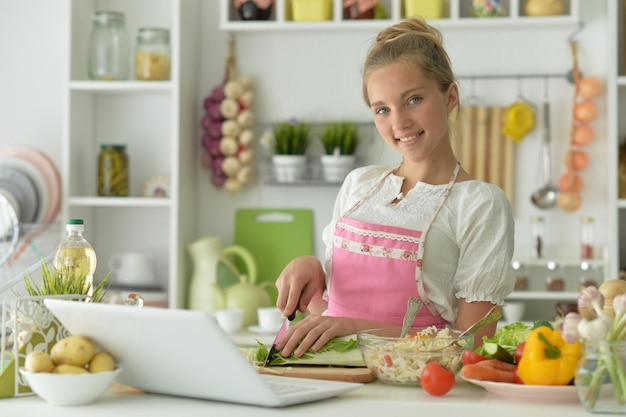 Ragazza carina che fa insalata in cucina