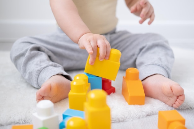 Ragazza carina che gioca in un colorato costruttore di plastica sul pavimento di casa Sviluppo della prima infanzia