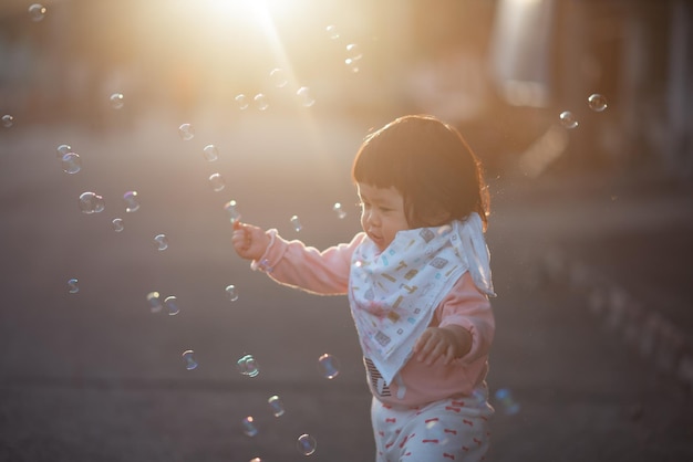Ragazza carina che guarda le bolle mentre è in piedi sulla strada