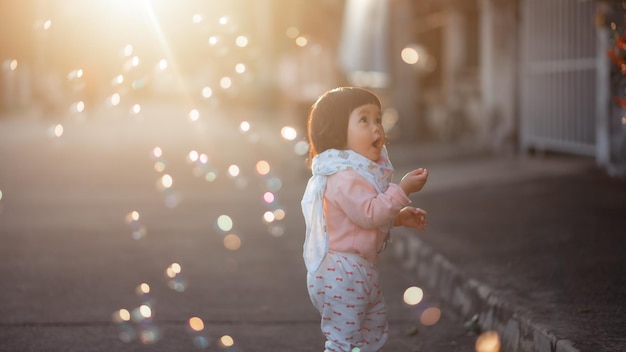 Ragazza carina che guarda le bolle mentre è in piedi sulla strada