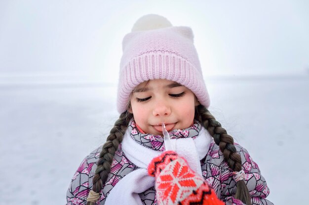 Ragazza carina che lecca il ghiaccio durante l'inverno