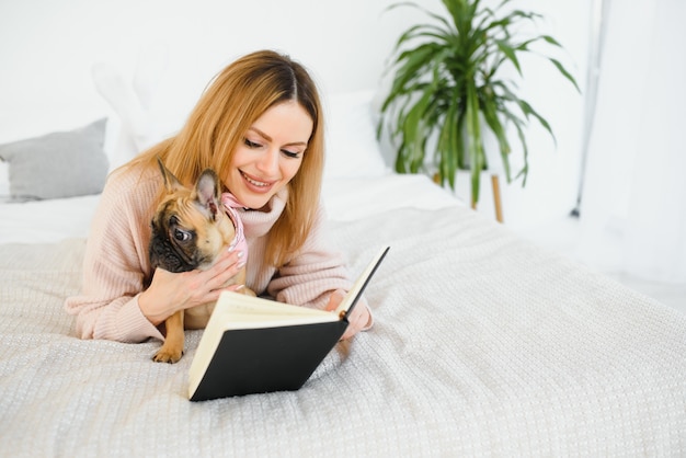 Ragazza carina che legge un libro con il suo cane a casa