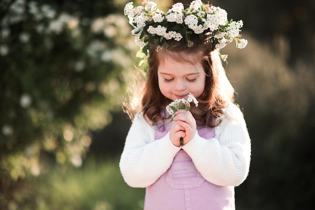 Ragazza carina che profuma fiori in giardino