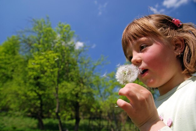 ragazza carina che soffia dundelion