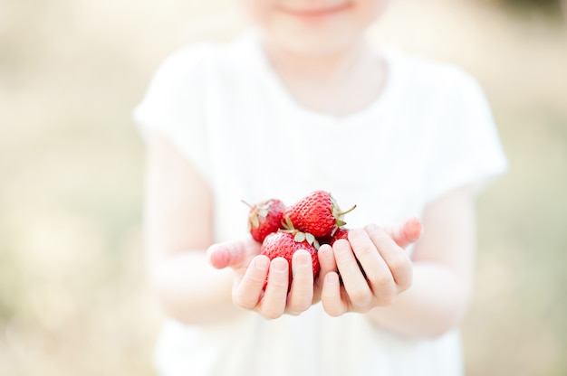 Ragazza carina che tiene fragola all'aperto