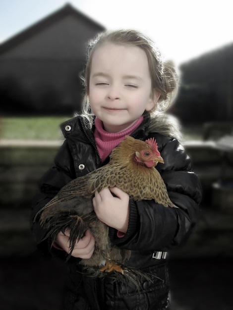 Ragazza carina con gli occhi chiusi che porta una gallina