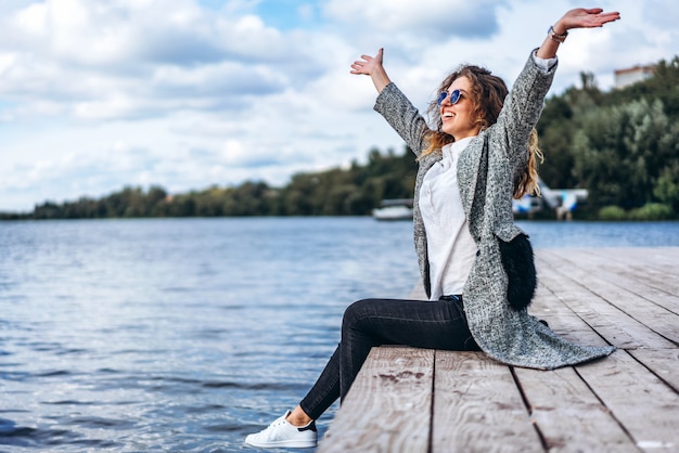 Ragazza carina con i capelli ricci rilassanti vicino al lago