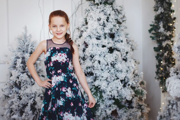 Ragazza carina con un bel vestito vicino a un albero di Natale