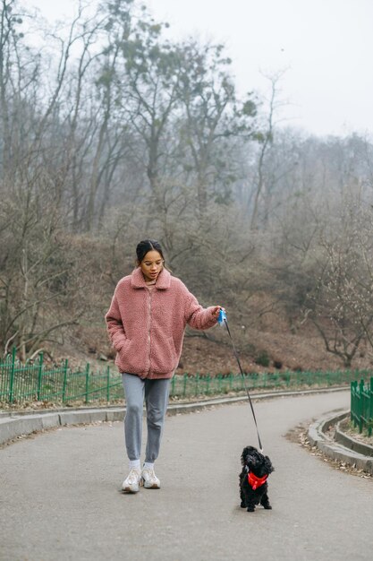 Ragazza carina con un cane divertente che cammina per strada Tempo libero con il tuo animale domestico