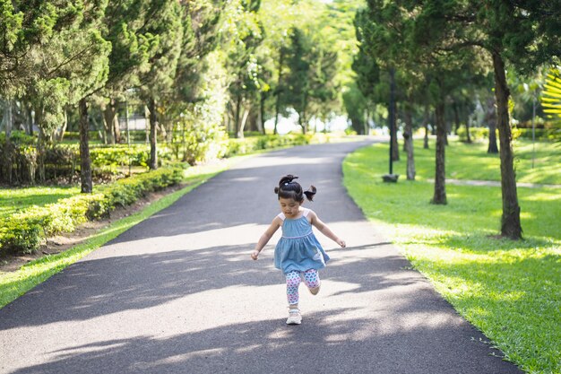 Ragazza carina felice che sorride e corre in giardino