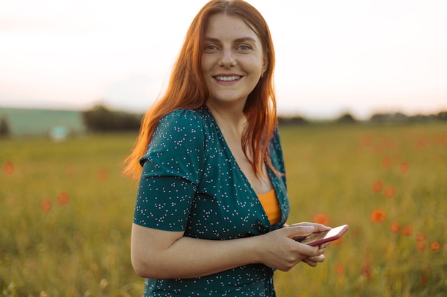 Ragazza carina felice che utilizza il telefono cellulare all'aperto nel parco naturale