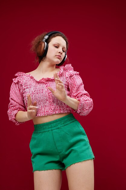 Ragazza carina in abiti colorati che posano musica con le cuffie inalterate