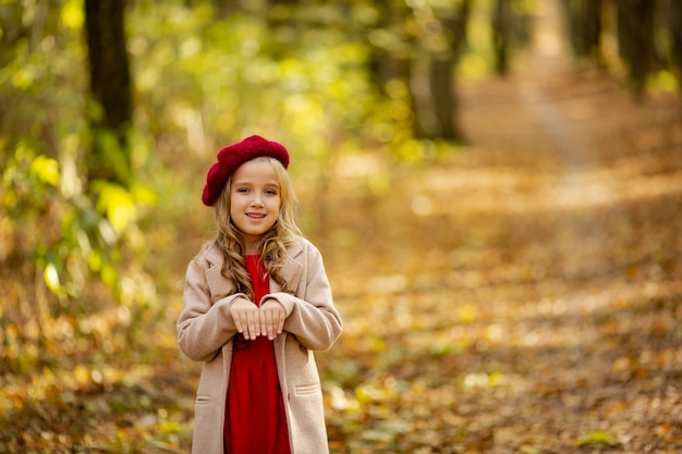 Ragazza carina in berretto rosso su una passeggiata in autunno