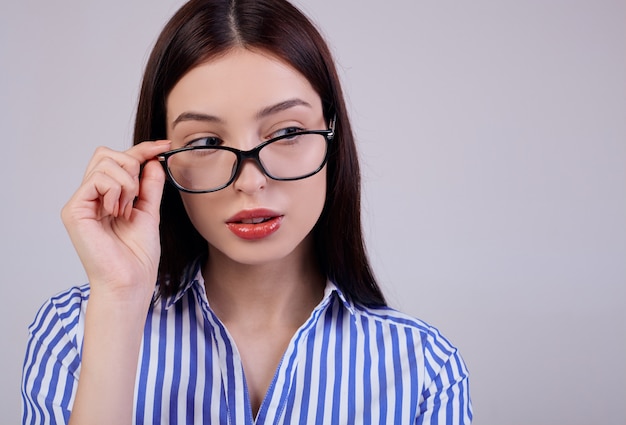 Ragazza carina in camicia a righe e occhiali neri traslucidi