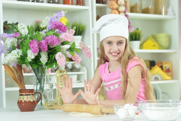 Ragazza carina in cappello da chef che produce pasta